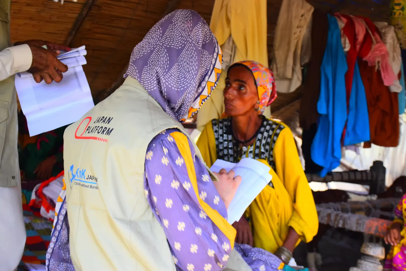 A KnK Japan team member records a household assessment with a woman at her home.