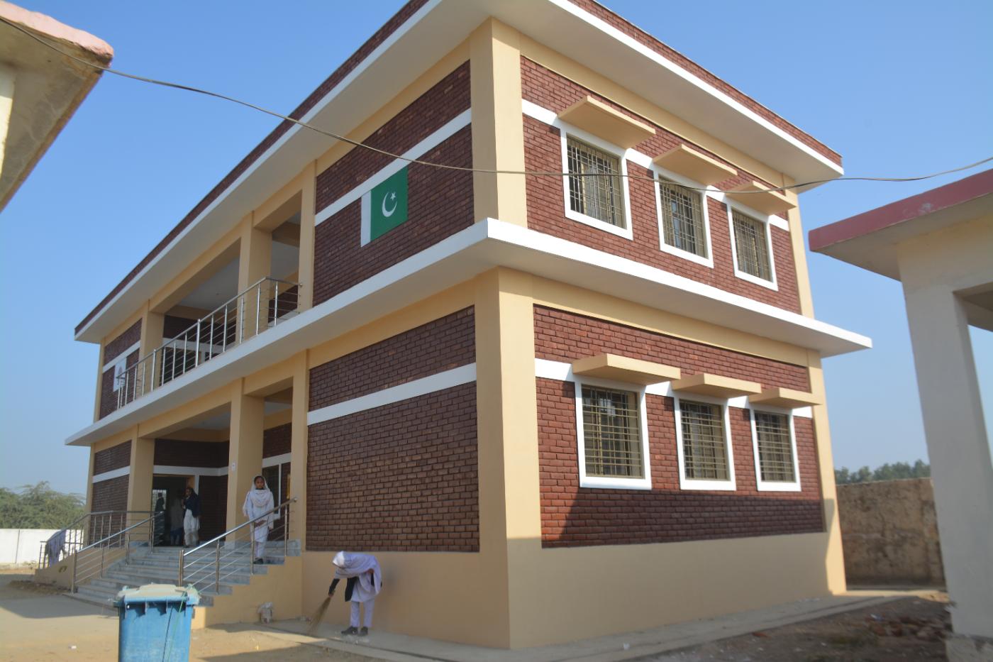 Corner view of a two-storey red-brick KnK Japan girls' high school on a raised plinth