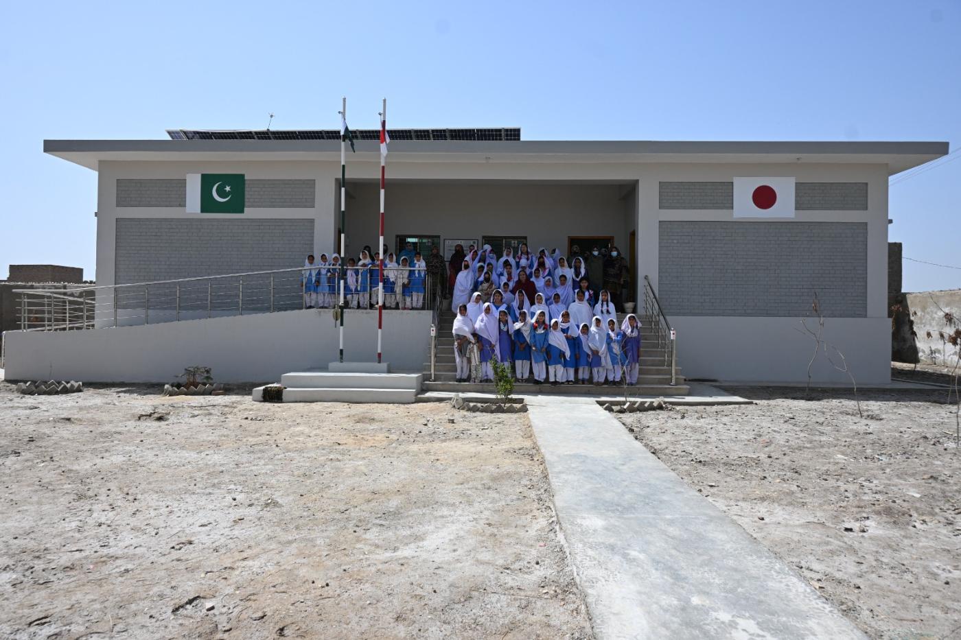 Students gathered for the handover of a newly built KnK Japan school with Pakistan and Japan flags